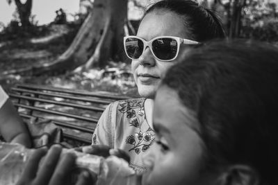 Portrait of woman wearing sunglasses sitting on bench