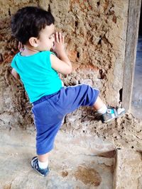 Side view of cute boy playing against wall