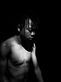 Shirtless boy against black background