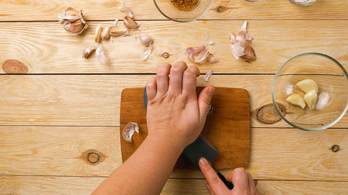 Close-up of women's hands crushing garlic cloves with a knife. top view. healthy and wholesome food