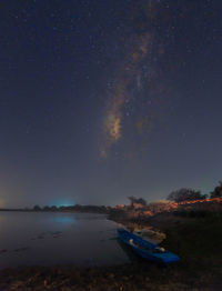 Rowboat on lakeshore against star field sky