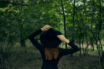 Rear view of woman standing in forest