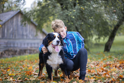 Outdoor portrait of boy with bernese mountain dog in autumn. friendship of teenager with pet.