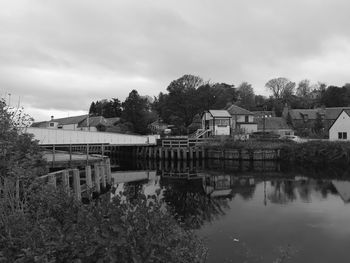 Houses by lake and buildings against sky