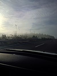 Cars on road against cloudy sky