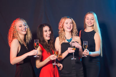 Happy young woman drinking glasses against blurred background