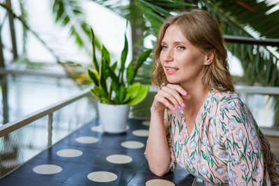 Middle aged pretty woman sitting in cafeteria in dress happy smiling. happy