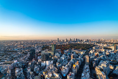 High angle view of city buildings against blue sky