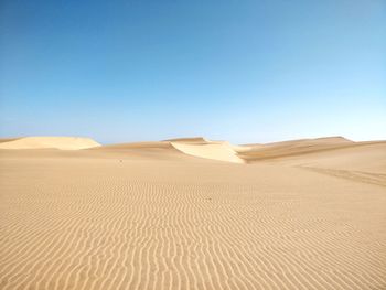 Scenic view of desert against clear blue sky