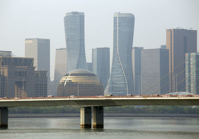 Bridge over river by buildings against sky in city