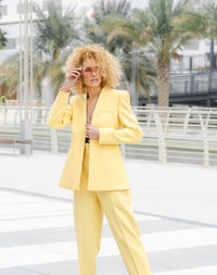 Urban style street fashion photosoot young girl with curly hair wearing yellow trendy suit 