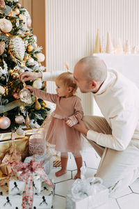 Happy dad and little girl daughter give gift boxes and decorate the christmas tree for the holiday