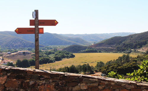 Information sign on hill against sky during sunny day