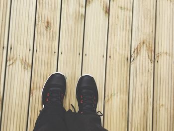 Low section of person standing on hardwood floor