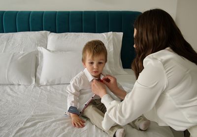 Mother with her toddler while putting on clothes for his birthday