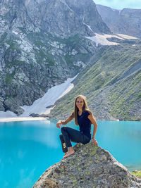 Portrait of woman sitting on rock by lake