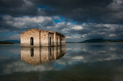 Reflection of building in lake against sky