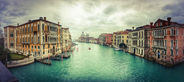 Canal with buildings alongside against sky