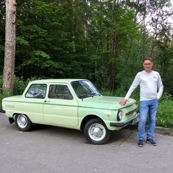 Portrait of young man standing by car