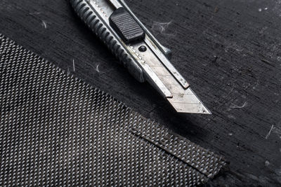 Close-up of utility knife with carbon fiber on workbench