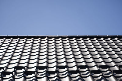 Low angle view of roof tiles against building against clear blue sky