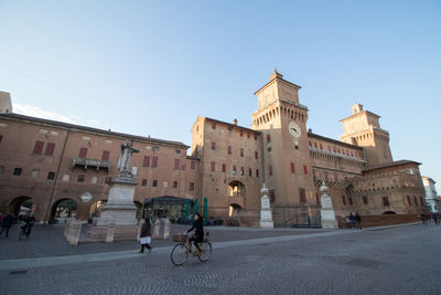 People on street by castello estense against sky