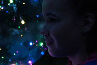 Close-up portrait of teenage girl looking away at night