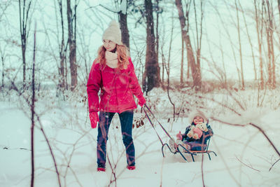 Mother and daughter wearing warm clothing playing in snow during winter