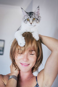 Close-up of cat on woman head at home