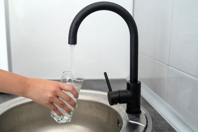 Cropped hand of woman filling water in glass