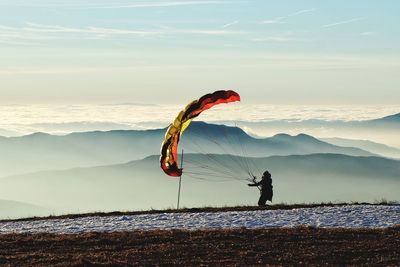 Person paragliding on mountain against sky
