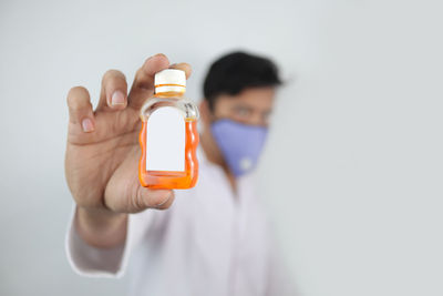 Portrait of man holding bottle against white background