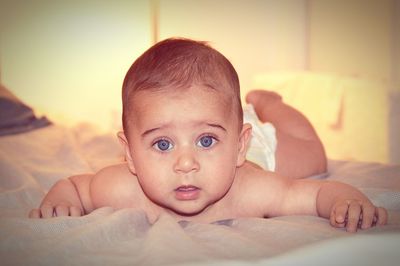 Close-up portrait of cute boy relaxing on bed at home