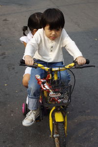 High angle view of siblings riding bicycle on street