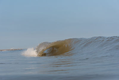 Waves splashing in sea against clear sky