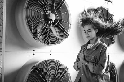 Teenage girl standing against exhaust fans