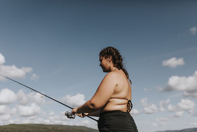 Rear view of man standing at beach against sky