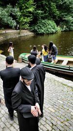 Rear view of people standing by lake