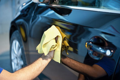 Midsection of man holding yellow car