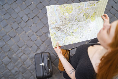 Red hair woman with trolley hold a city map on sanpietrini