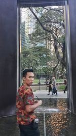 Woman standing by glass window in rainy season