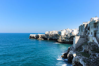 Sea by buildings against clear blue sky