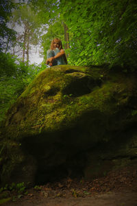 Woman sitting on rock in forest