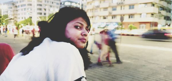 Portrait of young woman looking away on street in city