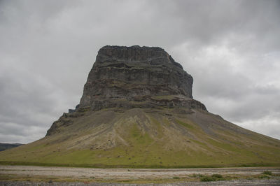 Low angle view of rock formation against cloudy sky