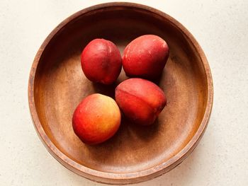 Four nectarines in wooden bowl.overhead. fresh, colourful, juicy, sweet, nutritious, summer fruit.