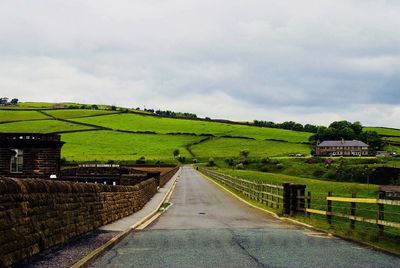 Road amidst agricultural landscape against sky