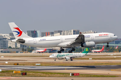 Airplane flying over airport runway against sky