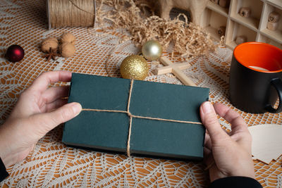 Women's hands holding box with gift. preparation for christmas holidays.