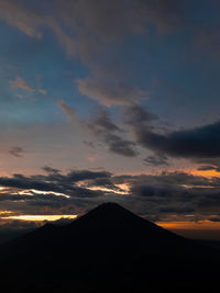 Low angle view of silhouette mountain against dramatic sky